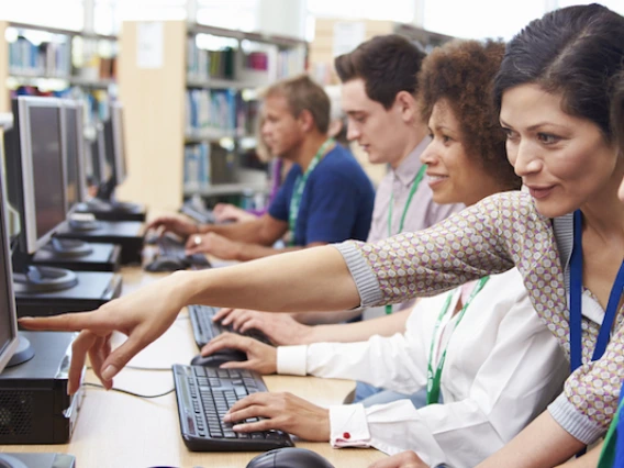 stock photo group of mature students working at computers with tutor